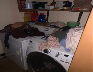 Laundry room with a washer and dryer buried under clothes before removal