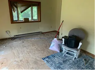 Bedroom nearly empty with one chair and a broom